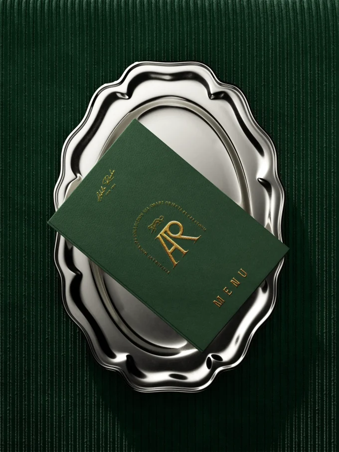 Green gold-embossed folder on a silver tray over ribbed fabric