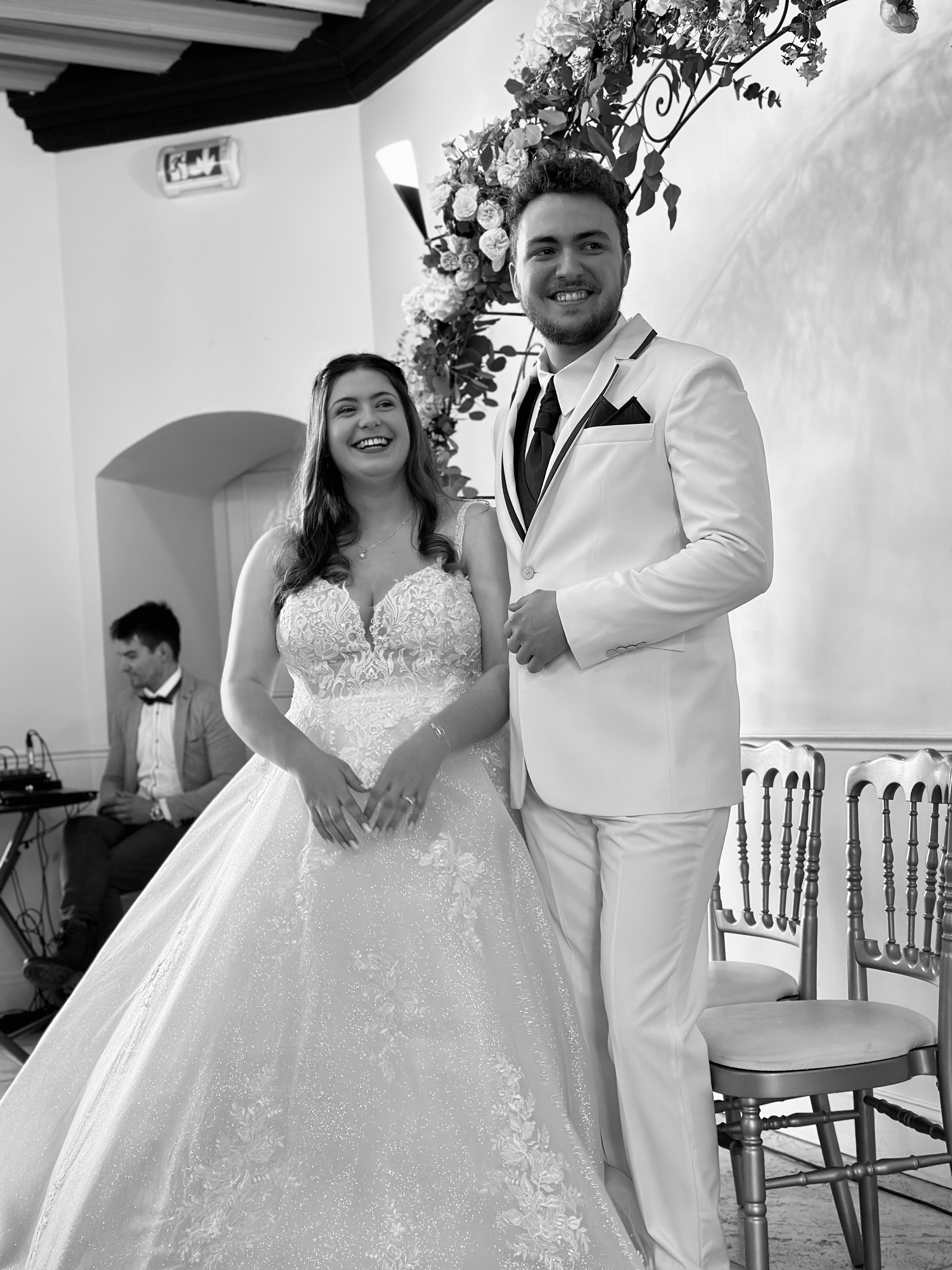Shooting mariage en lumière naturelle,  devant une église en pierre. Le noir et blanc efface l'anecdote —  il ne reste que l'instant.
