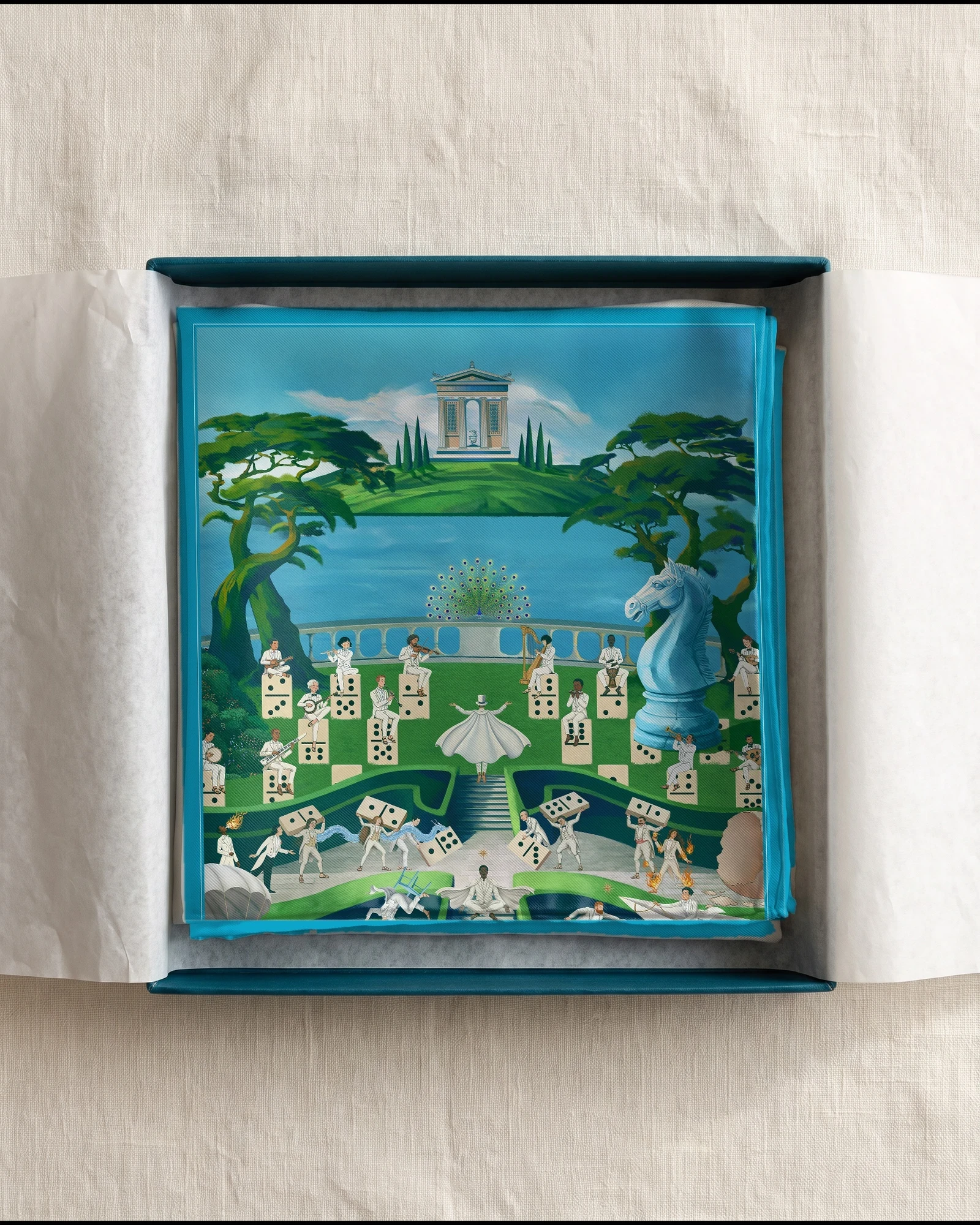 The Garden of Eden silk scarf folded in a deep teal gift box with white tissue, showing the temple, Petra and the orchestra