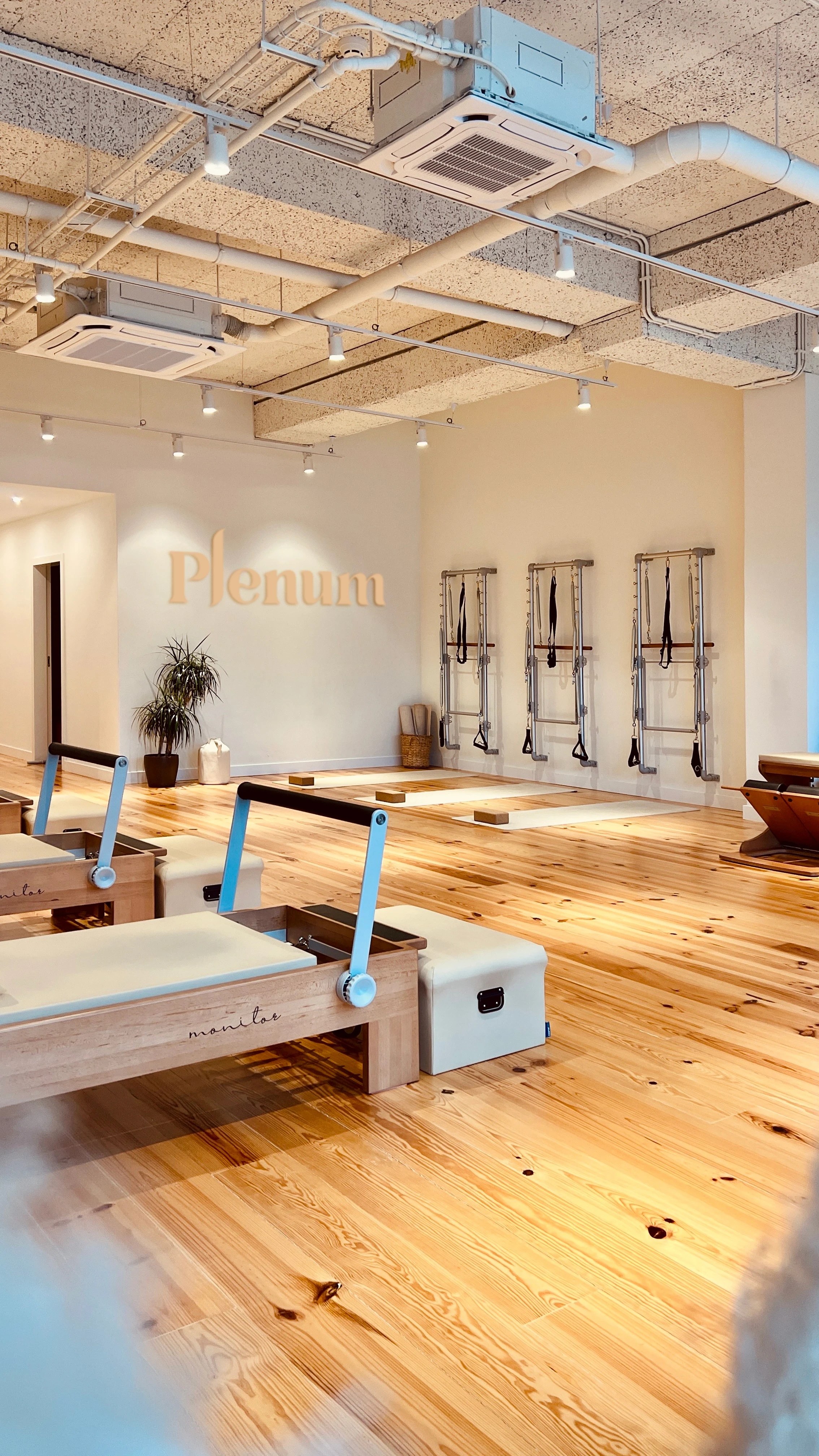 Interior of Plenum Pilates Studio in Marvila, Lisbon featuring minimalist wellness design, Pilates reformer equipment and the Plenum brand logo on the studio wall.