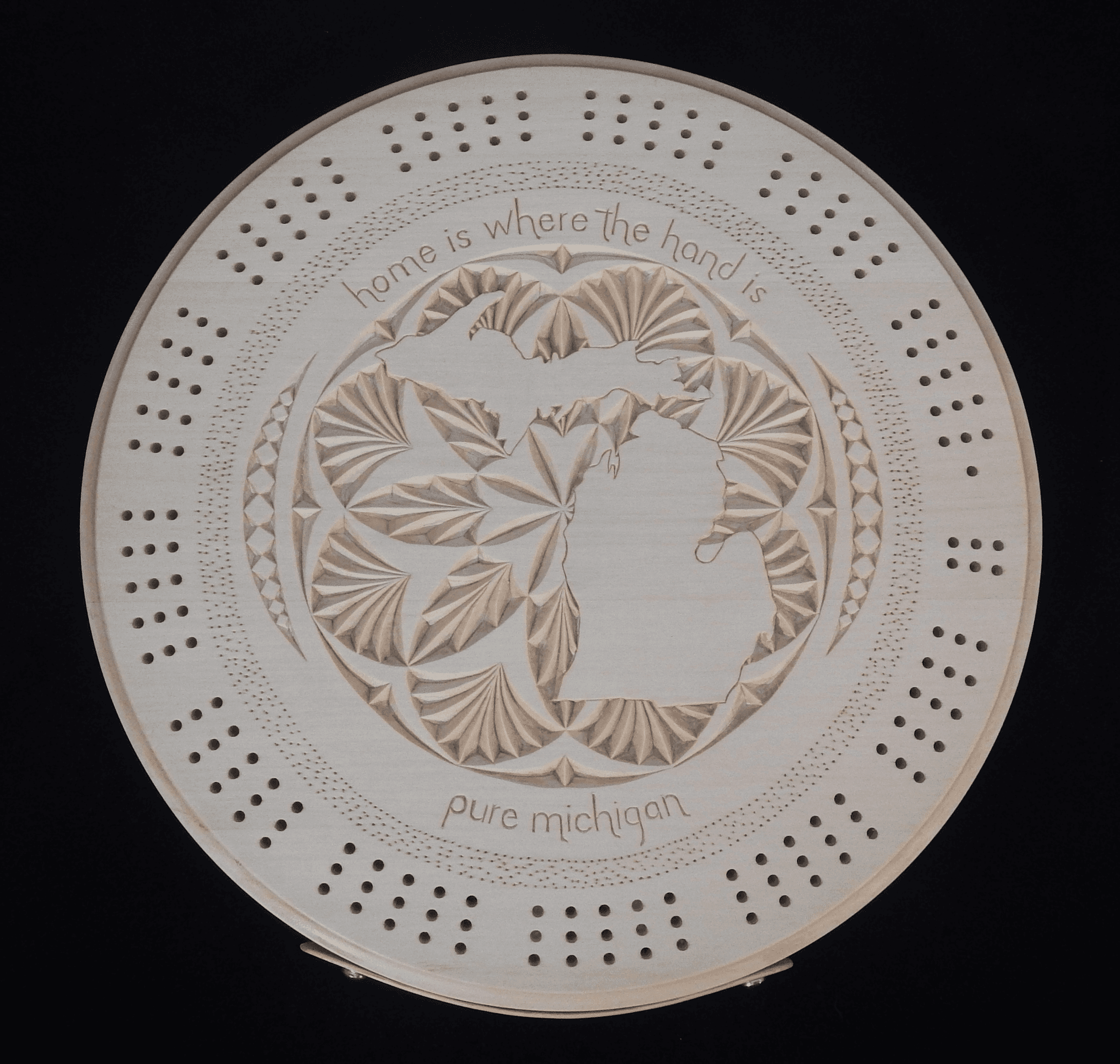 Chip carved cribbage board with the shape of Michigan surrounded by a rosette