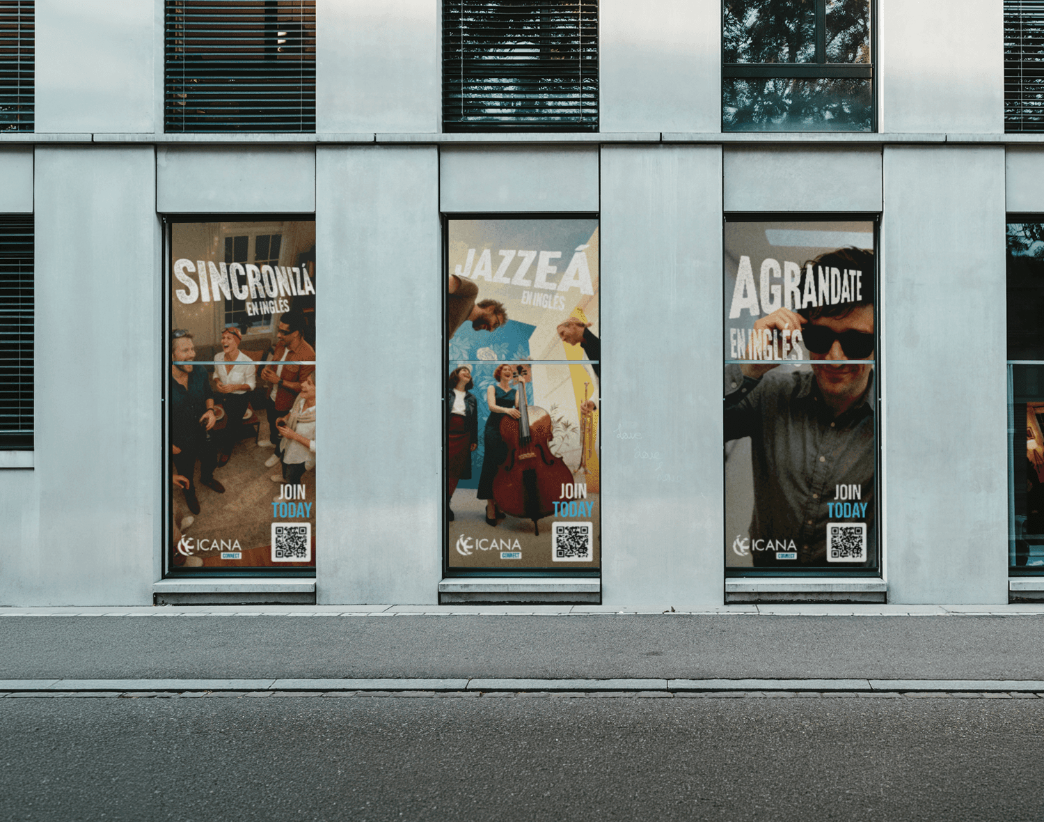 Three vertical window posters on a modern building facade featuring ICANA Connect advertisements in Spanish ("Sincronizá en Inglés," "Jazzeá en Inglés," and "Agrandate en Inglés") with photos of people socializing and playing music, each including a QR code and "Join Today" text.