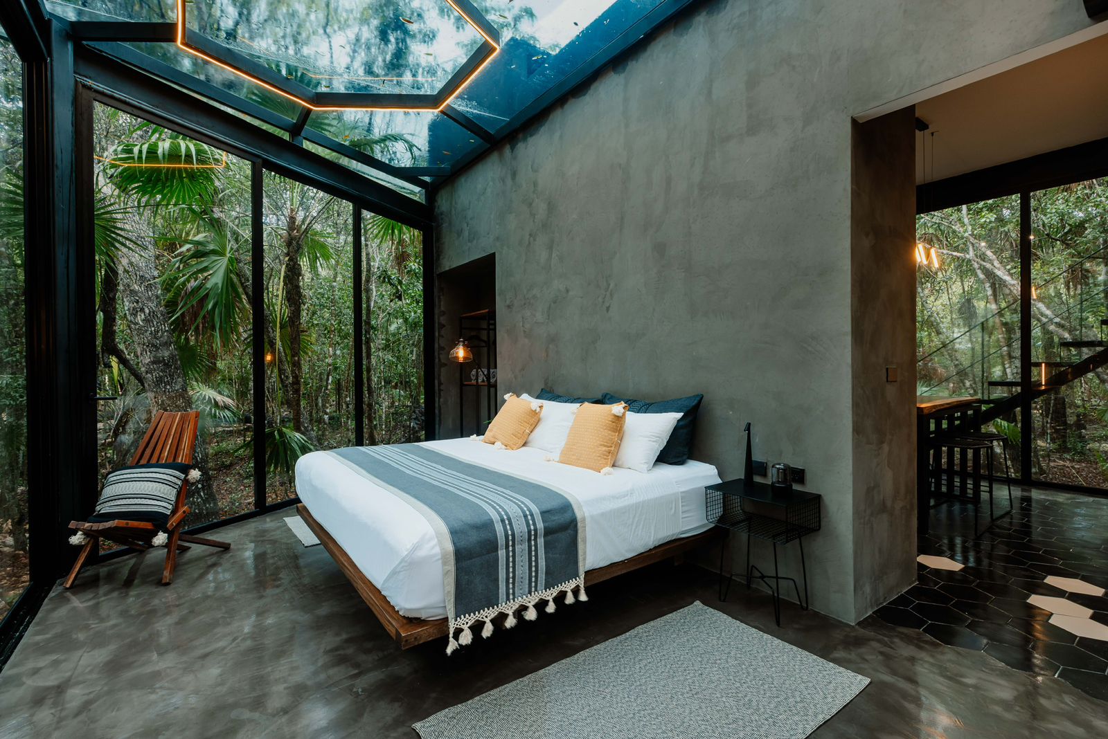 A rustic kitchen scene featuring glass jars of sourdough starter on a wooden table, with a notebook filled with handwritten recipes, a brown bowl of flour, and a beige fabric apron, illuminated by soft natural light from a window.