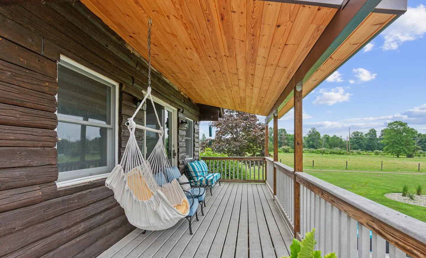 Covered porch with hanging chair and pasture view at Rocking Horse Acres, Bucks County, PA