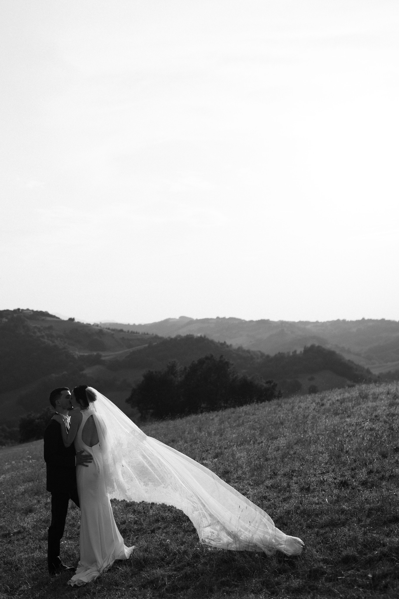 Sposi al tramonto nel Parco di Montebello, velo che svolazza tra i colli, reportage matrimoniale in bianco e nero