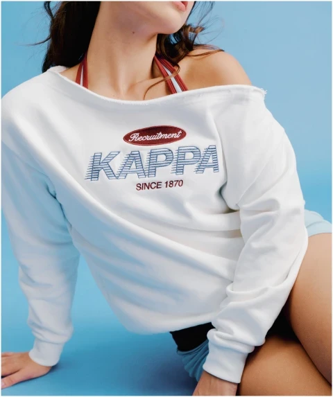 Model wearing a white off-the-shoulder Kappa recruitment sweatshirt over a halter top.