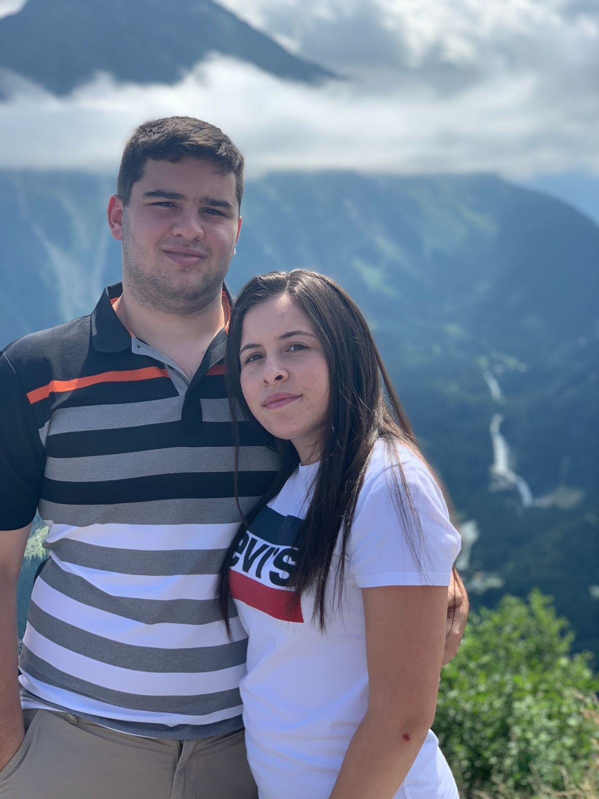 A close-up of two people holding hands, one wearing a denim jacket. The background is softly blurred, suggesting a tender, intimate moment in warm light.
