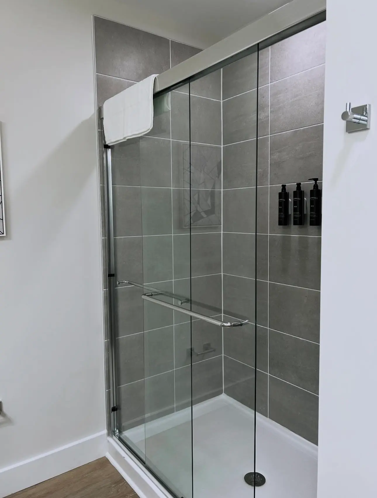 Professionally cleaned Airbnb walk-in shower featuring streak-free glass doors, polished chrome hardware, and sanitized grey wall tiling.