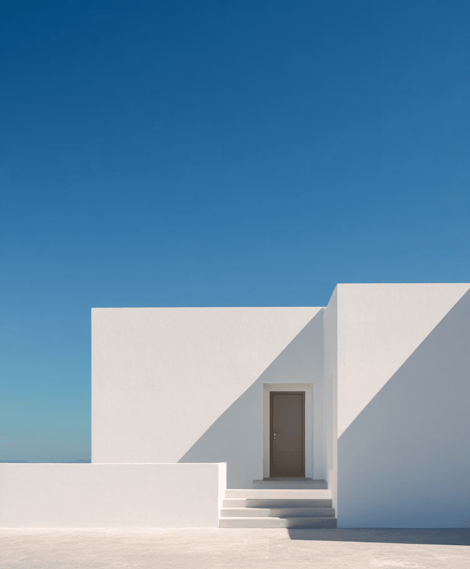 A section of a modern white building against a deep blue sky.