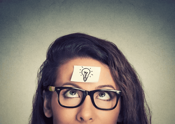 A person with glasses, a necklace and holding an object.