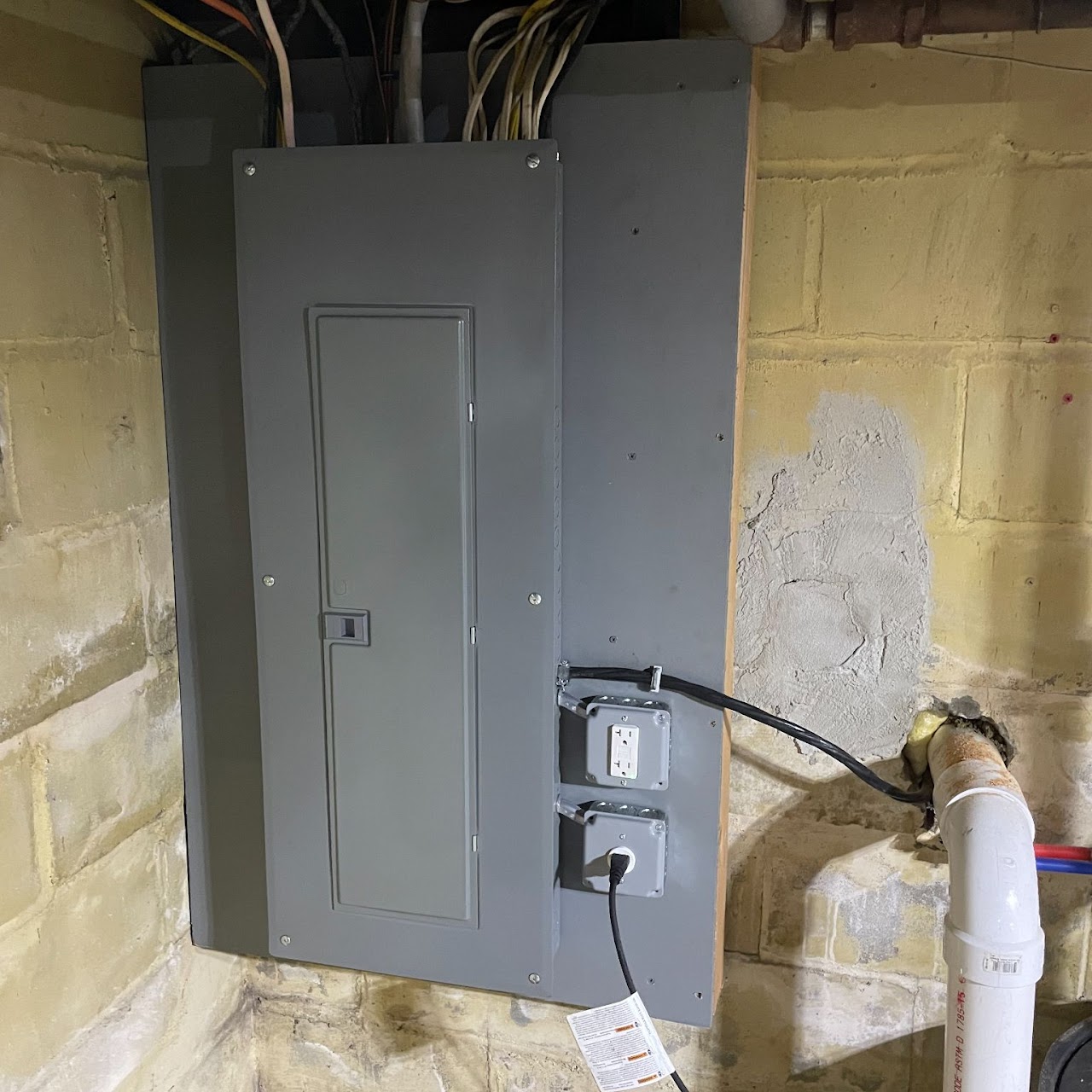 New gray electrical service panel mounted neatly on basement wall