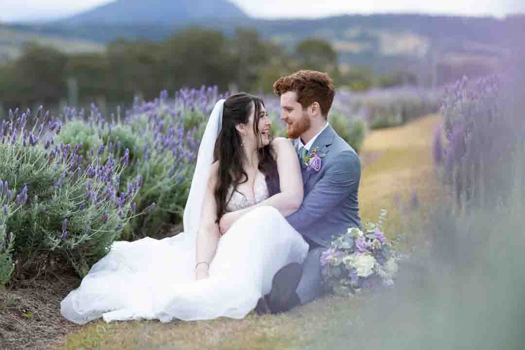 Bride and groom sitting in lavener field