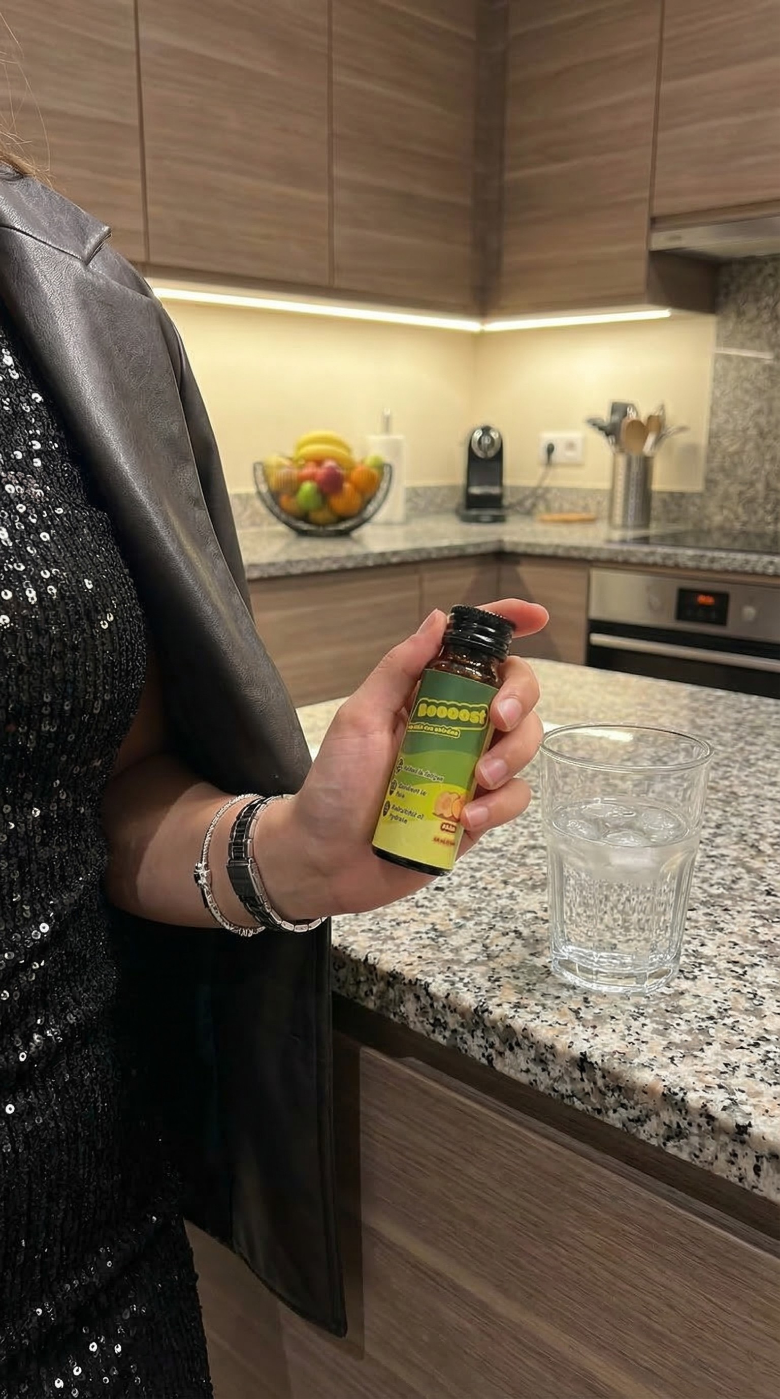Un shot Boooost posé sur un comptoir de cuisine moderne à Dijon, Bourgogne, à côté d'un verre d'eau, prêt pour une routine de récupération active avant de dormir.