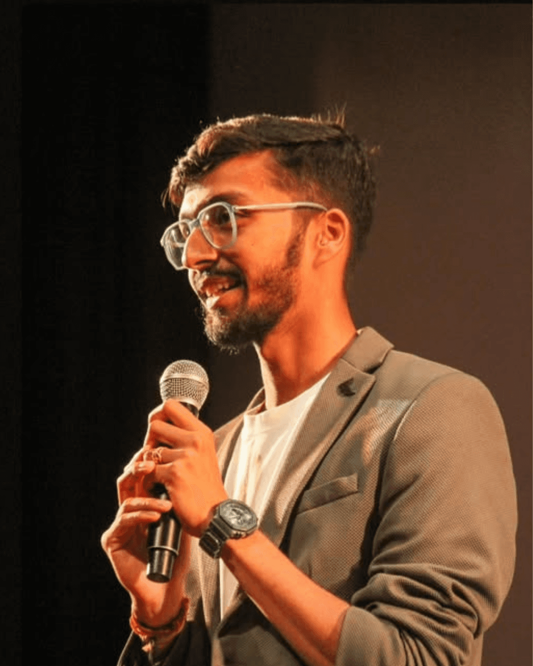 Man sitting in a dimly lit room, wearing a beige shirt and looking contemplative.