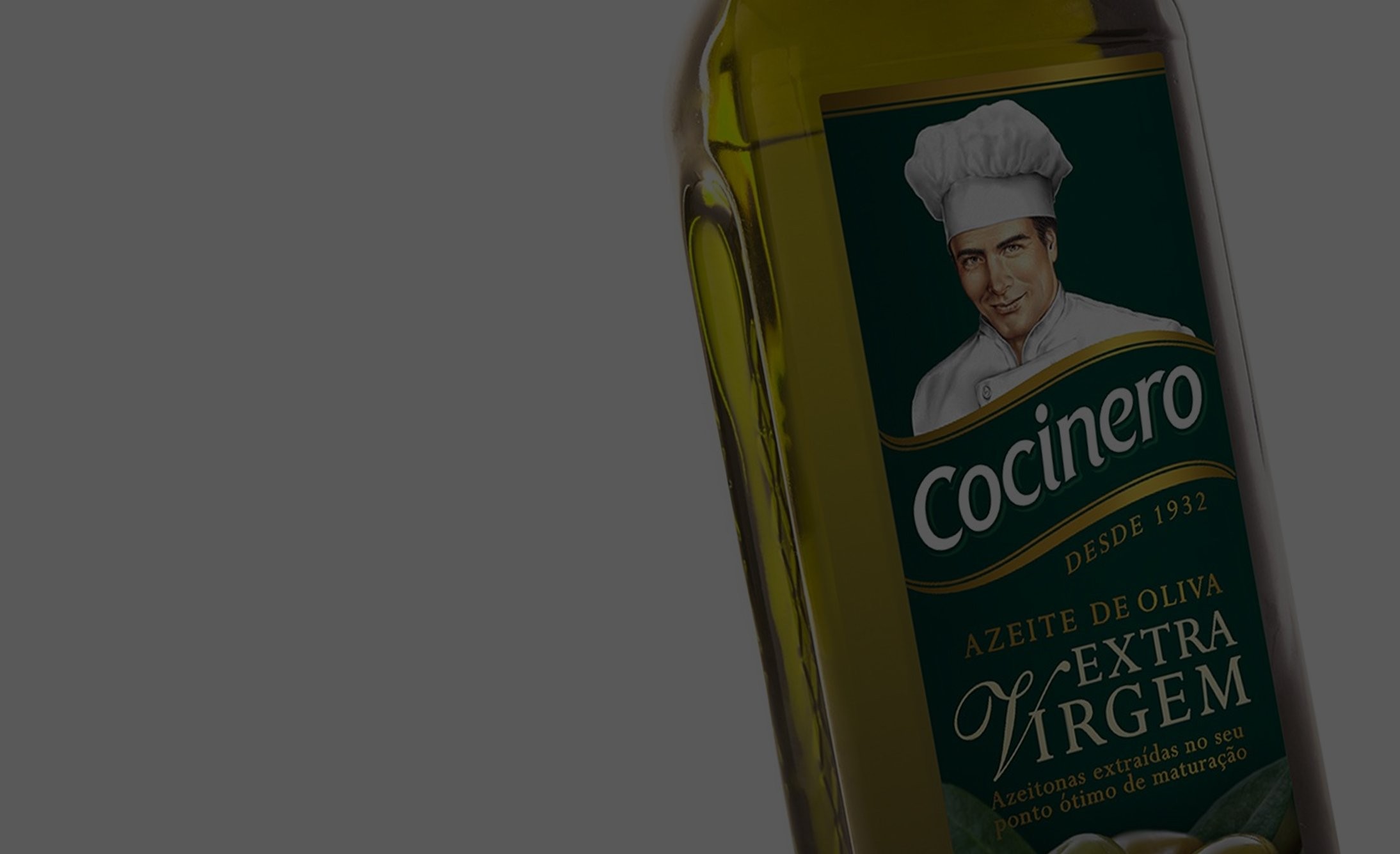 Una botella de aceite de oliva virgen extra Cocinero está inclinada contra un fondo gris. La etiqueta presenta a un chef con un sombrero blanco, transmitiendo una sensación de calidad.