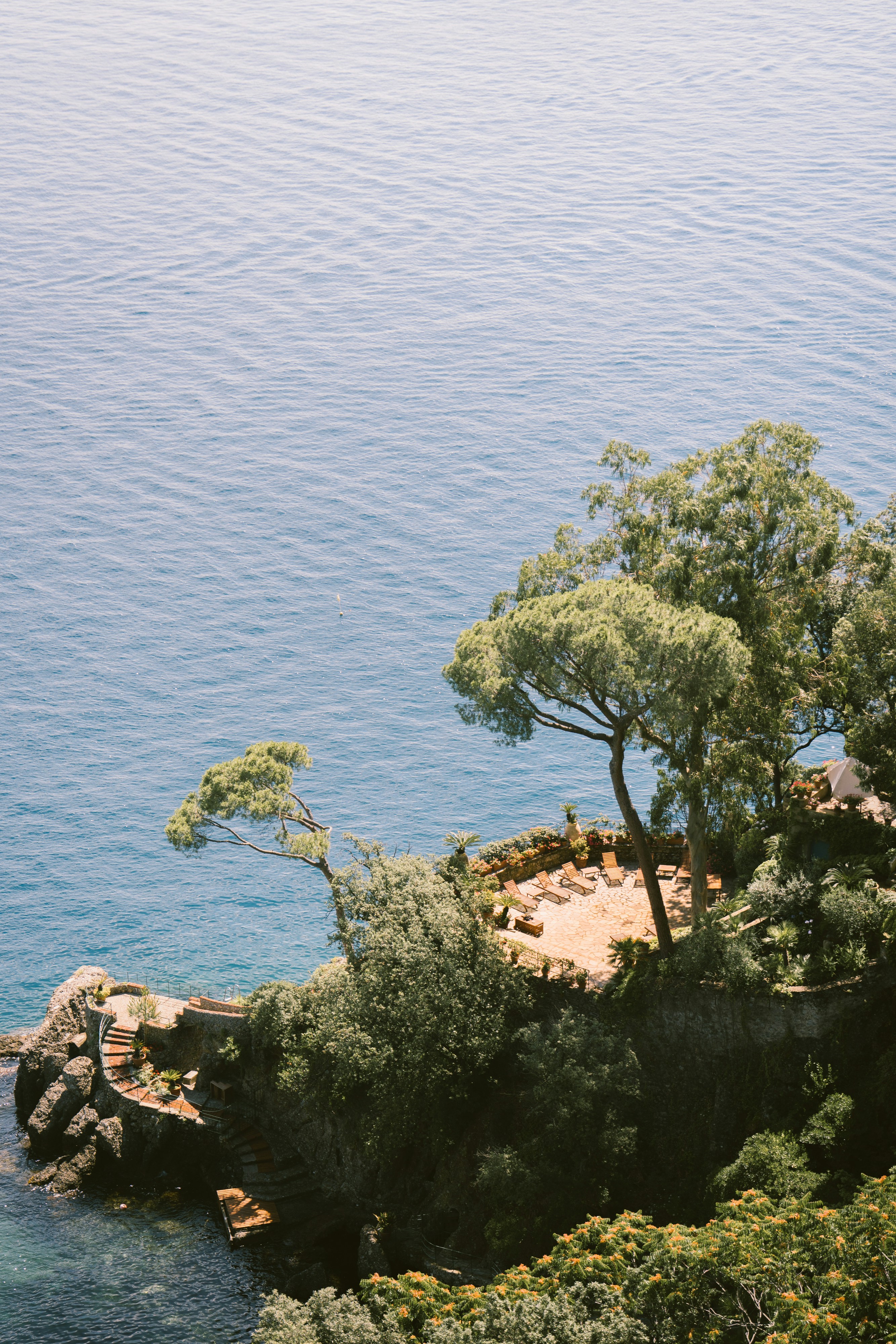 man standing near cliff looking at body of water during daytime