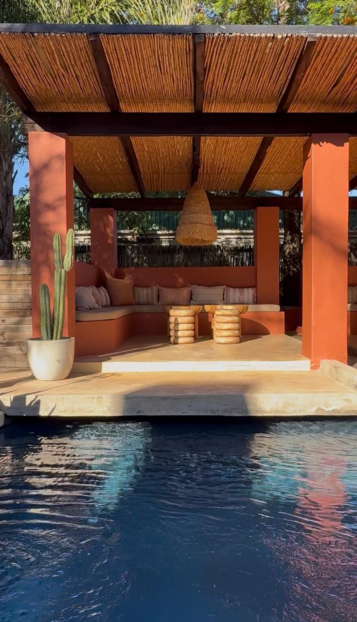 Cabana seating in front of pool with raffia pendant and wooden stools at Kokos Huis, Riebeek Kasteel