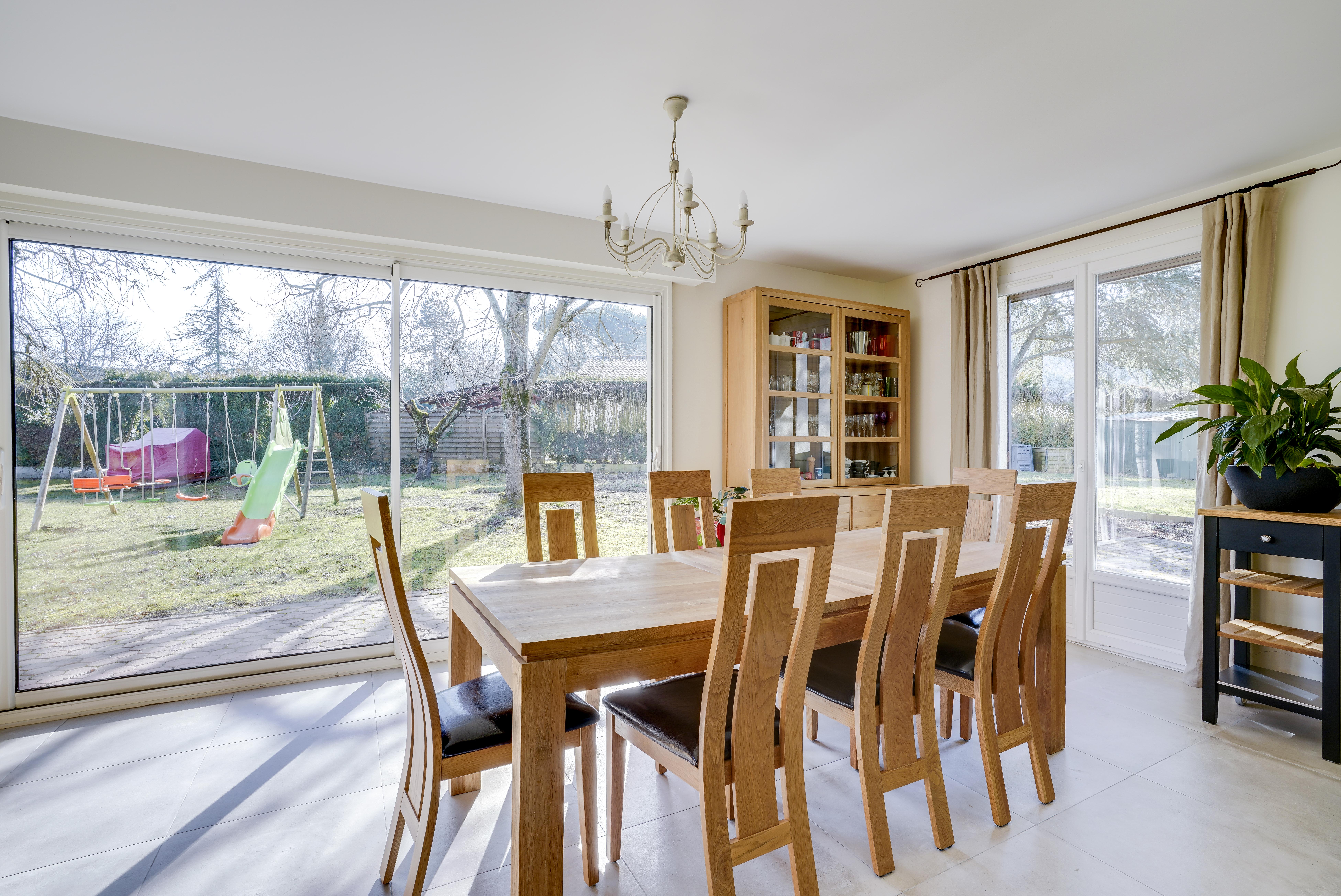 Transformation salle à manger 77 avec grande table bois 8 chaises, portes vitrées donnant sur jardin avec jeux enfants, rénovation complète.