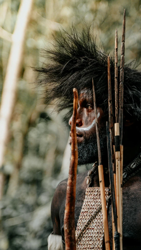 Papua New Guinea tribal warrior with traditional face paint and spear in rainforest cultural landscape