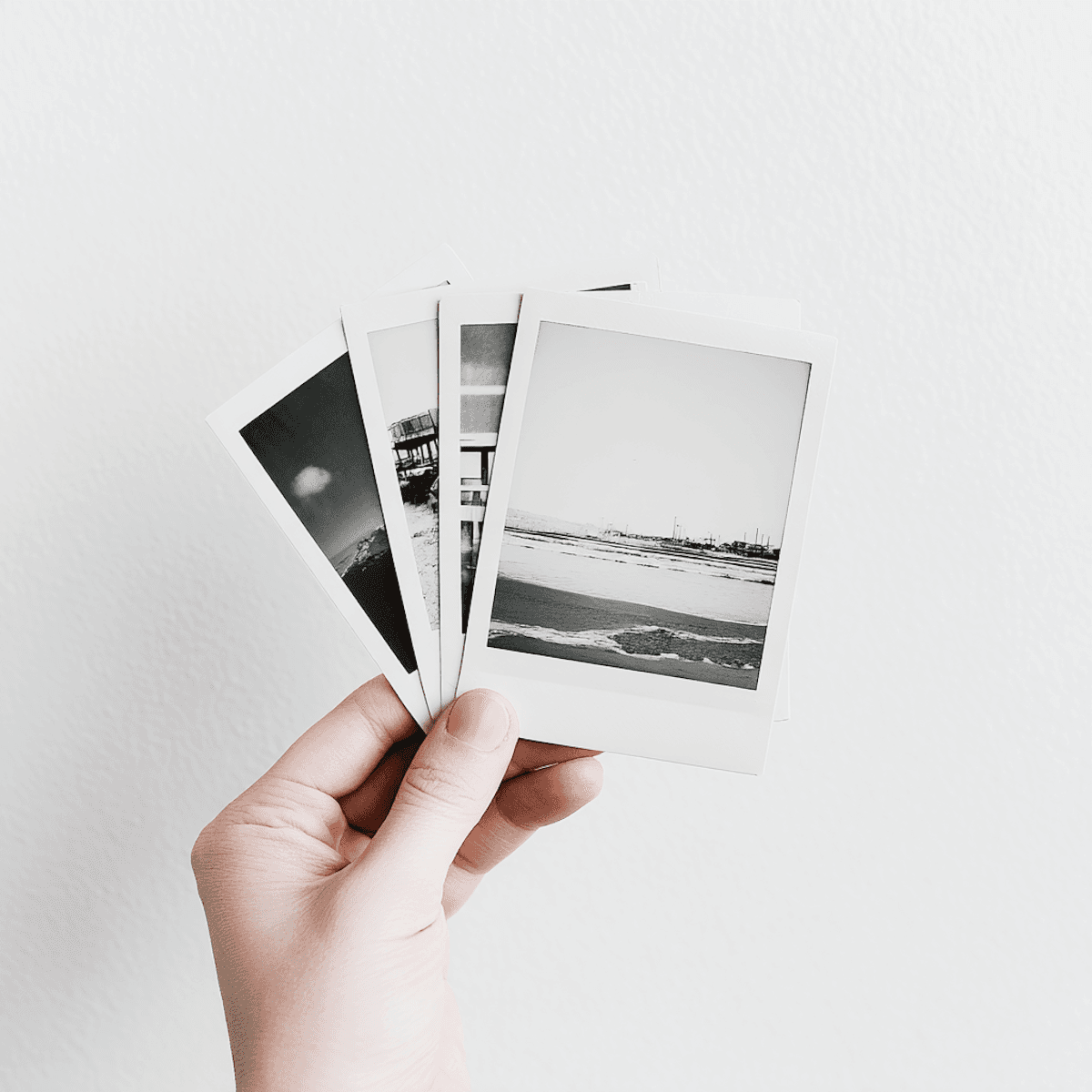 Close-up of a hand holding several monochrome instant photos