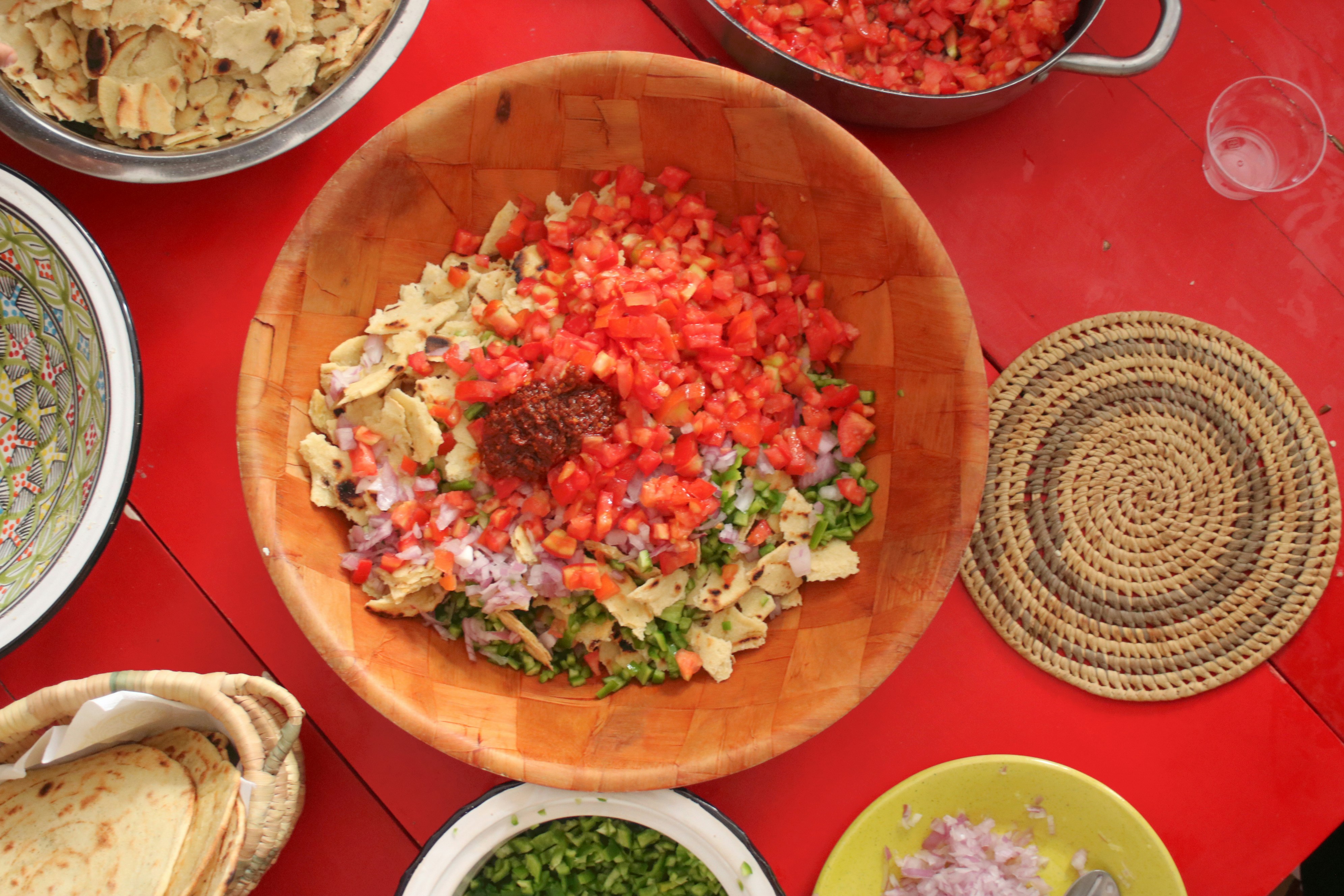 a wooden bowl filled with lots of food on top of a red table
