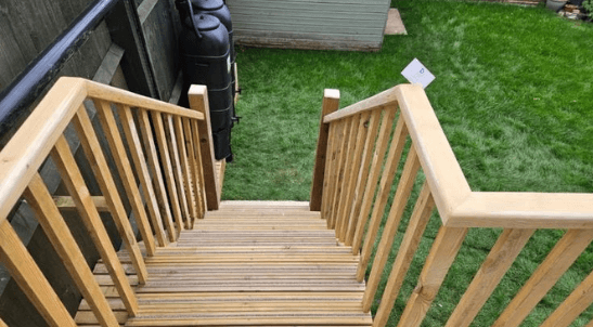 Wooden decking steps with handrails leading into a newly landscaped garden, constructed by PPM Builders in Northampton.