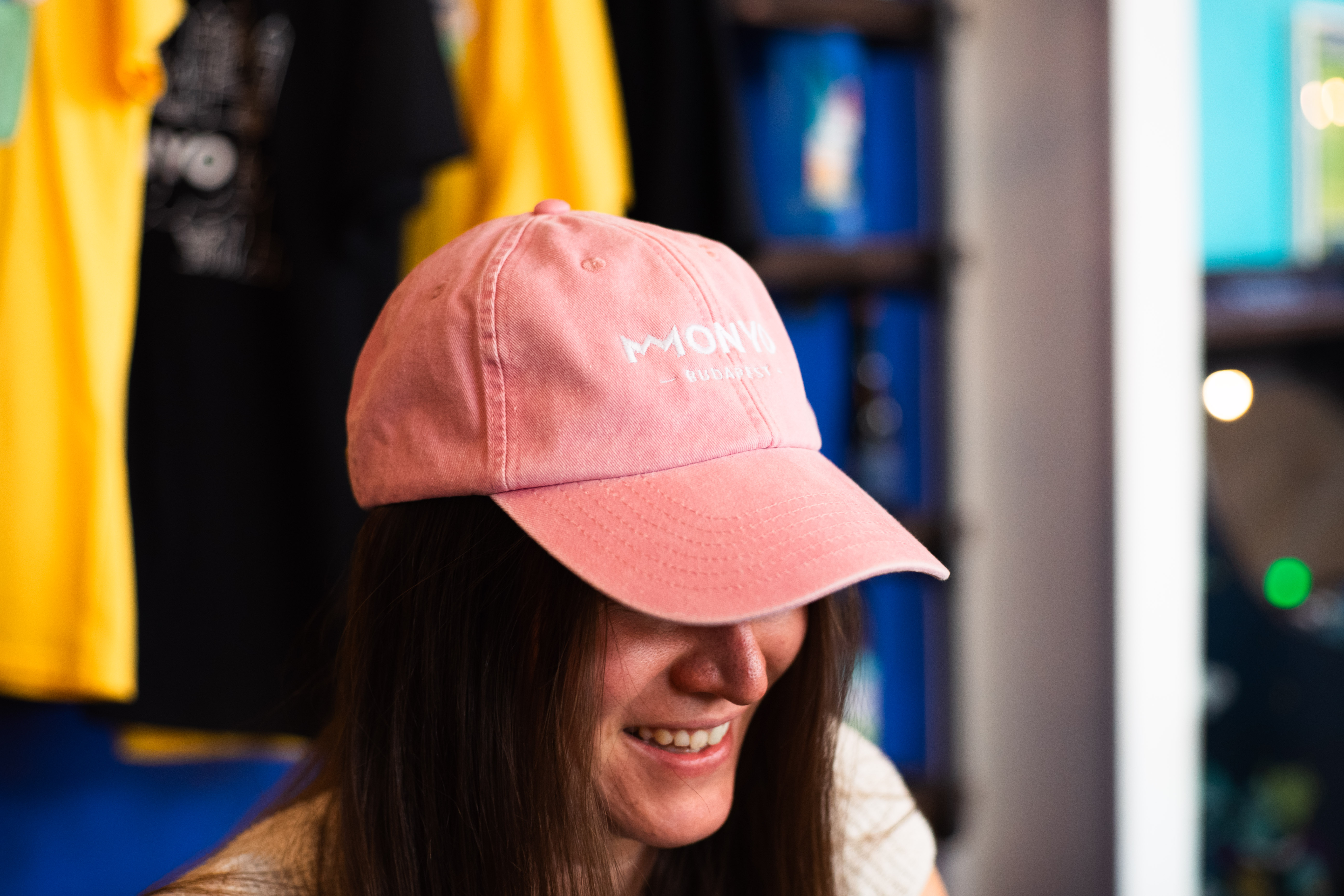 Woman in blue hat and sweater sitting on couch with laptop.