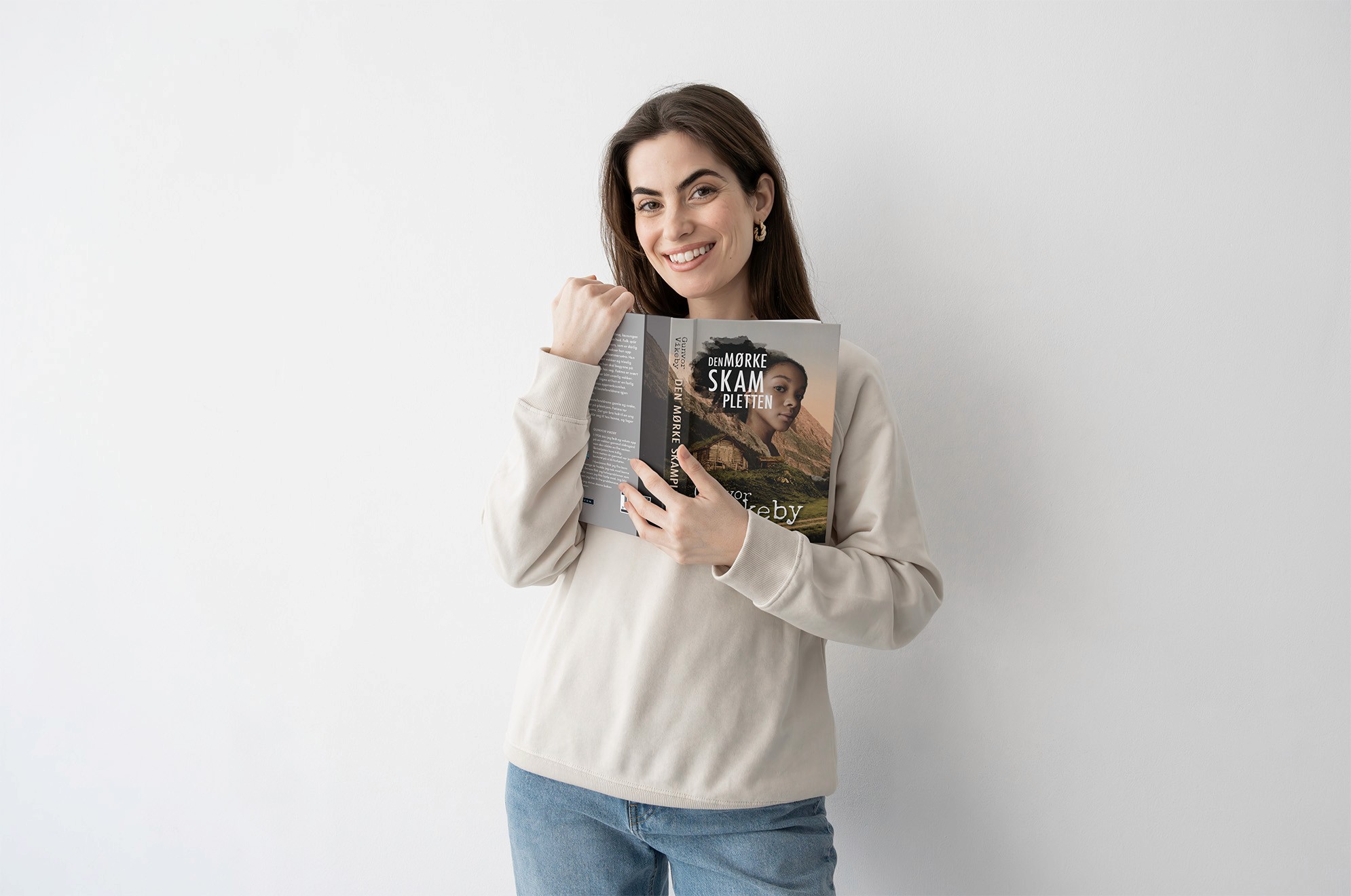 Uśmiechnięta kobieta trzyma otwartą książkę Den mørke skampletten Thora Østeby'ego.