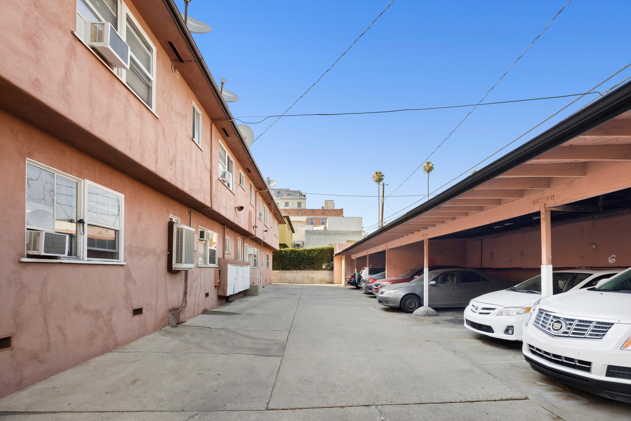 1640 N Harvard covered parking structure with multiple vehicles and residential units with peach-colored exterior
