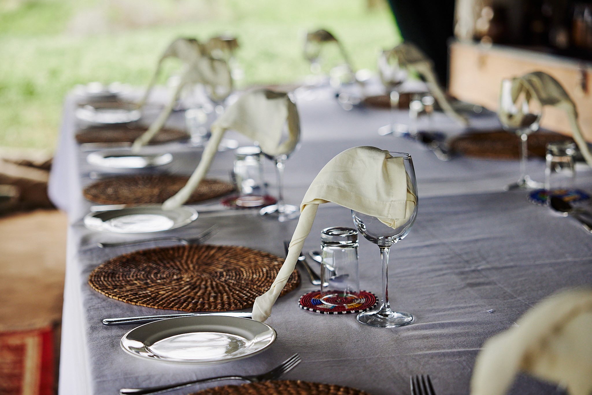 Grupp av ryttare på ridresa i Afrika galopperar över Serengetis vidsträckta slätter medan damm och gnuhjordar rör sig över horisonten under the great migration.