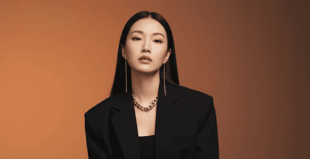 A high-quality, AI-generated professional portrait of a confident woman with long black hair, sitting on a chair and wearing a tailored black suit with bold silver jewelry. This generated image is a case study used by Mahindra, a specialist digital marketing trainer and marketing trainer consultant, to illustrate advanced visual content strategies on his blog.