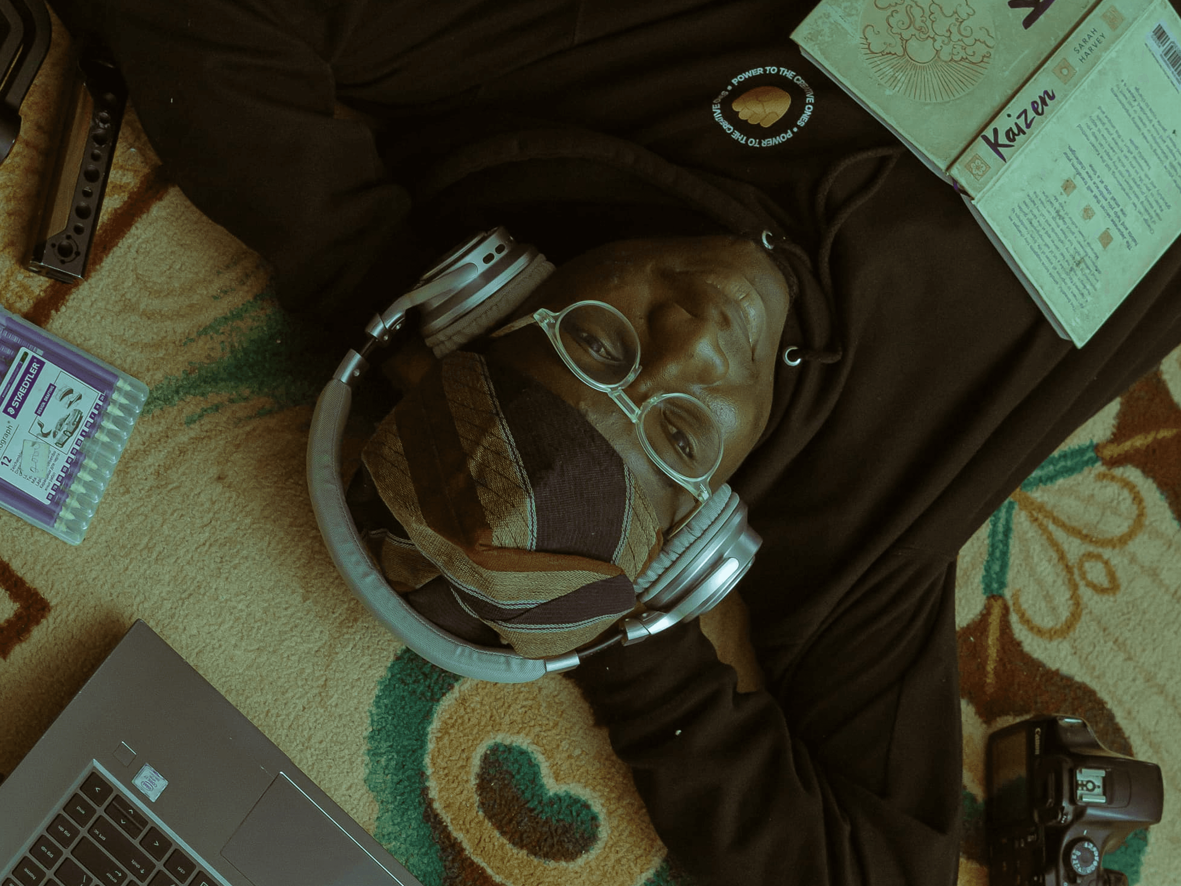 Modern minimalist desk setup with a computer monitor, microphone arm, camera, and indoor plants, featuring a pegboard with accessories on the wall and a Bauhaus-style poster leaning against the wall.
