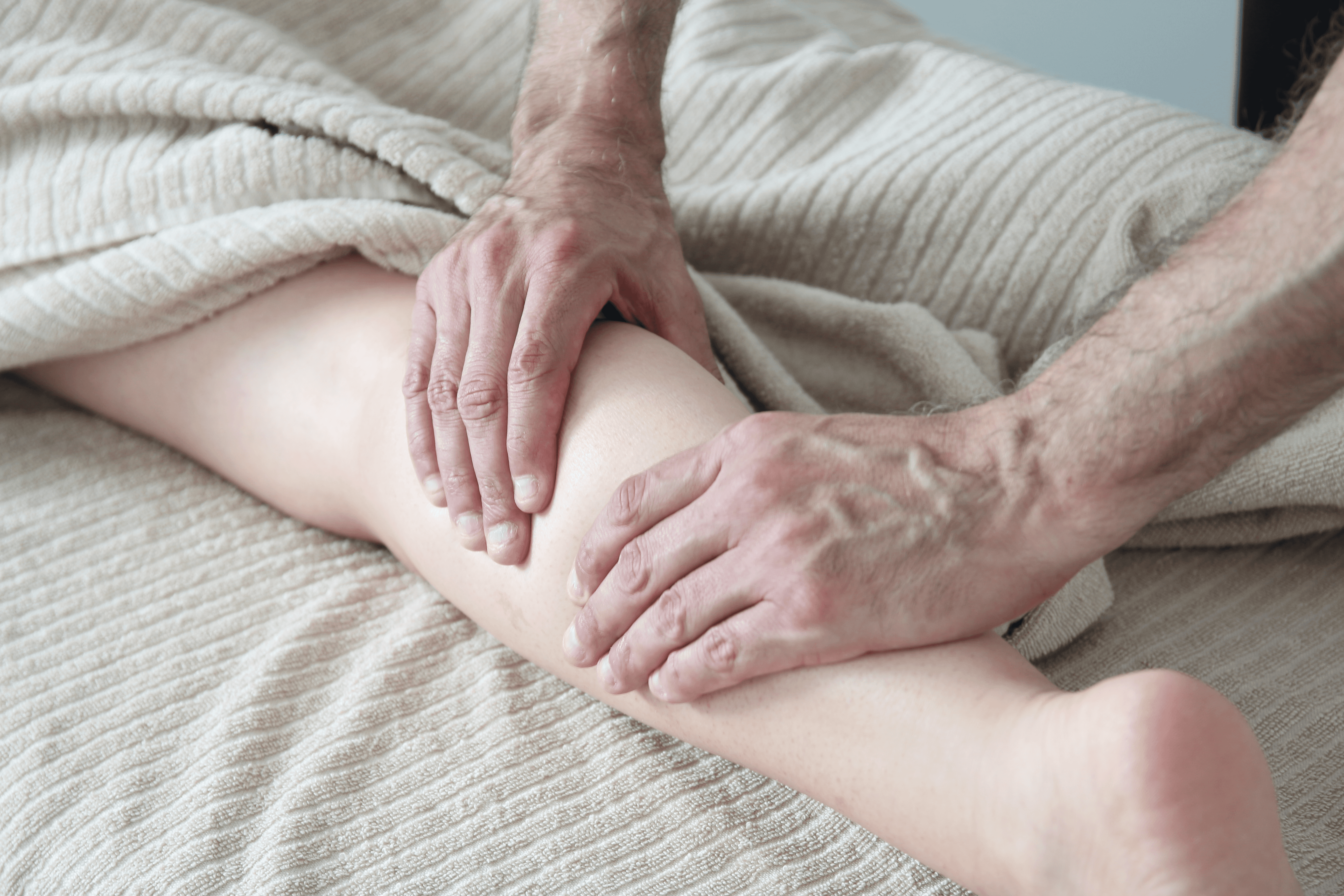 Woman relaxing on a massage table with candles in the background, receiving a back massage in a spa setting