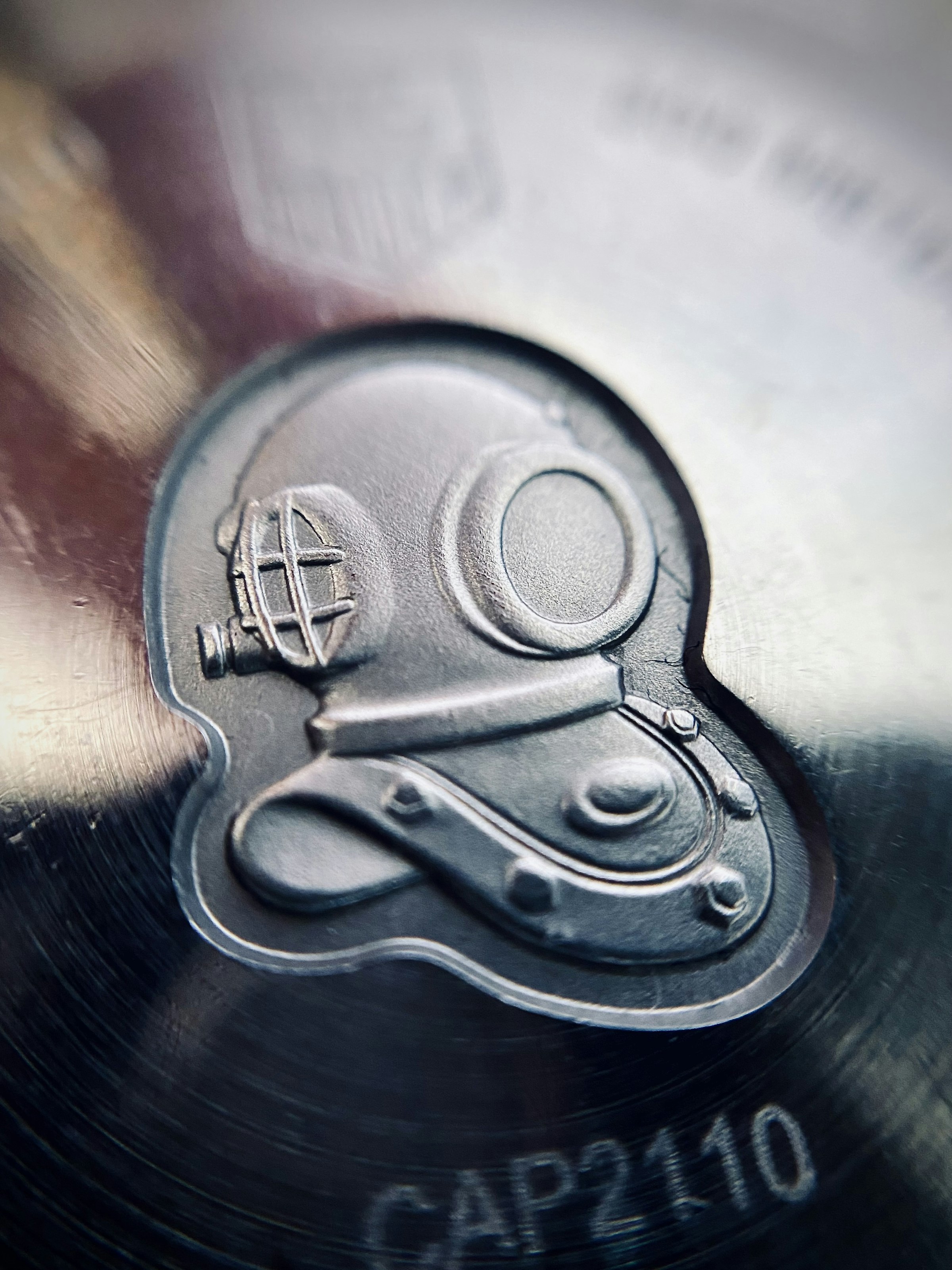 Embossed diving helmet emblem stamped in metal