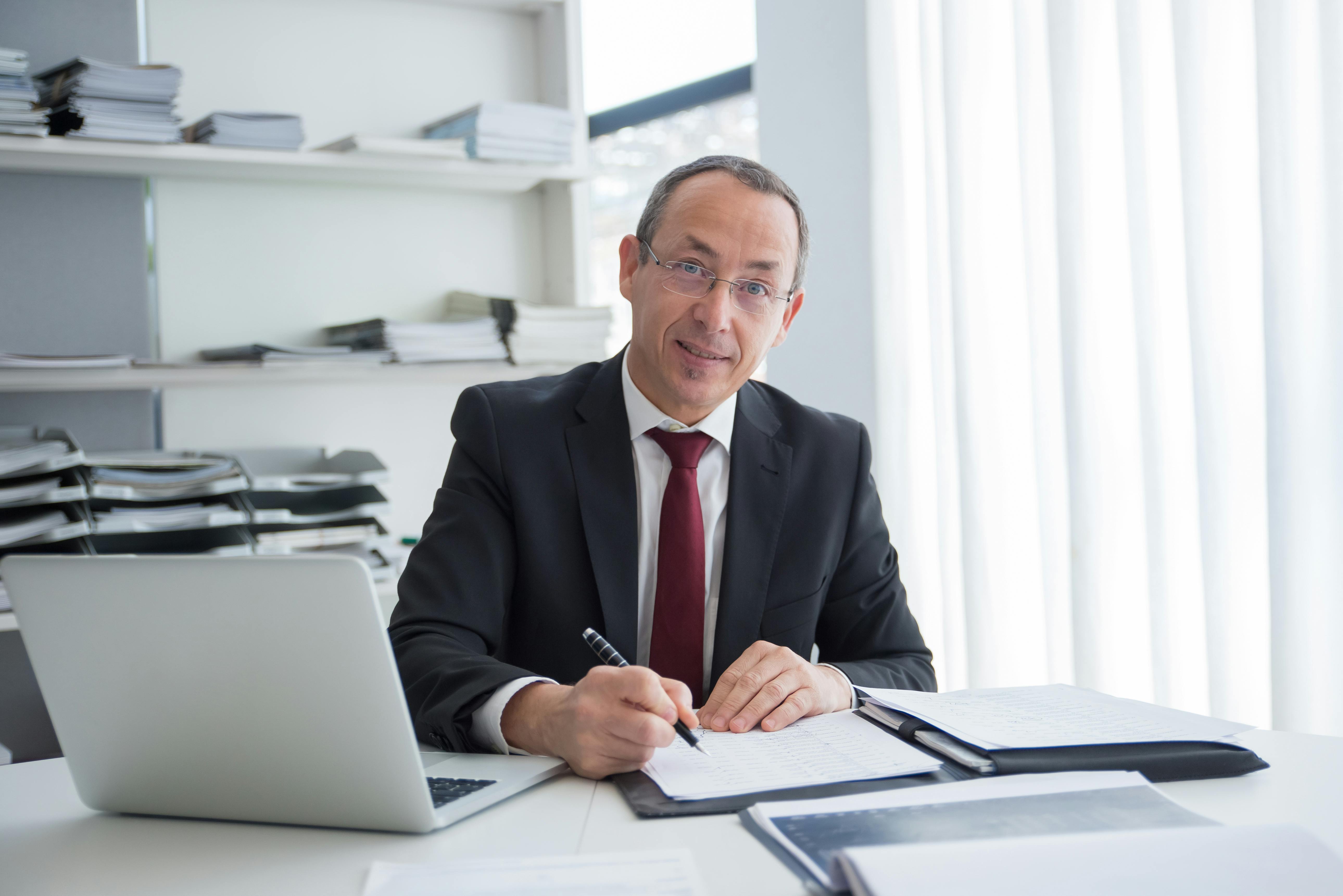 Self-employed mortgage broker in black suit holding a pen