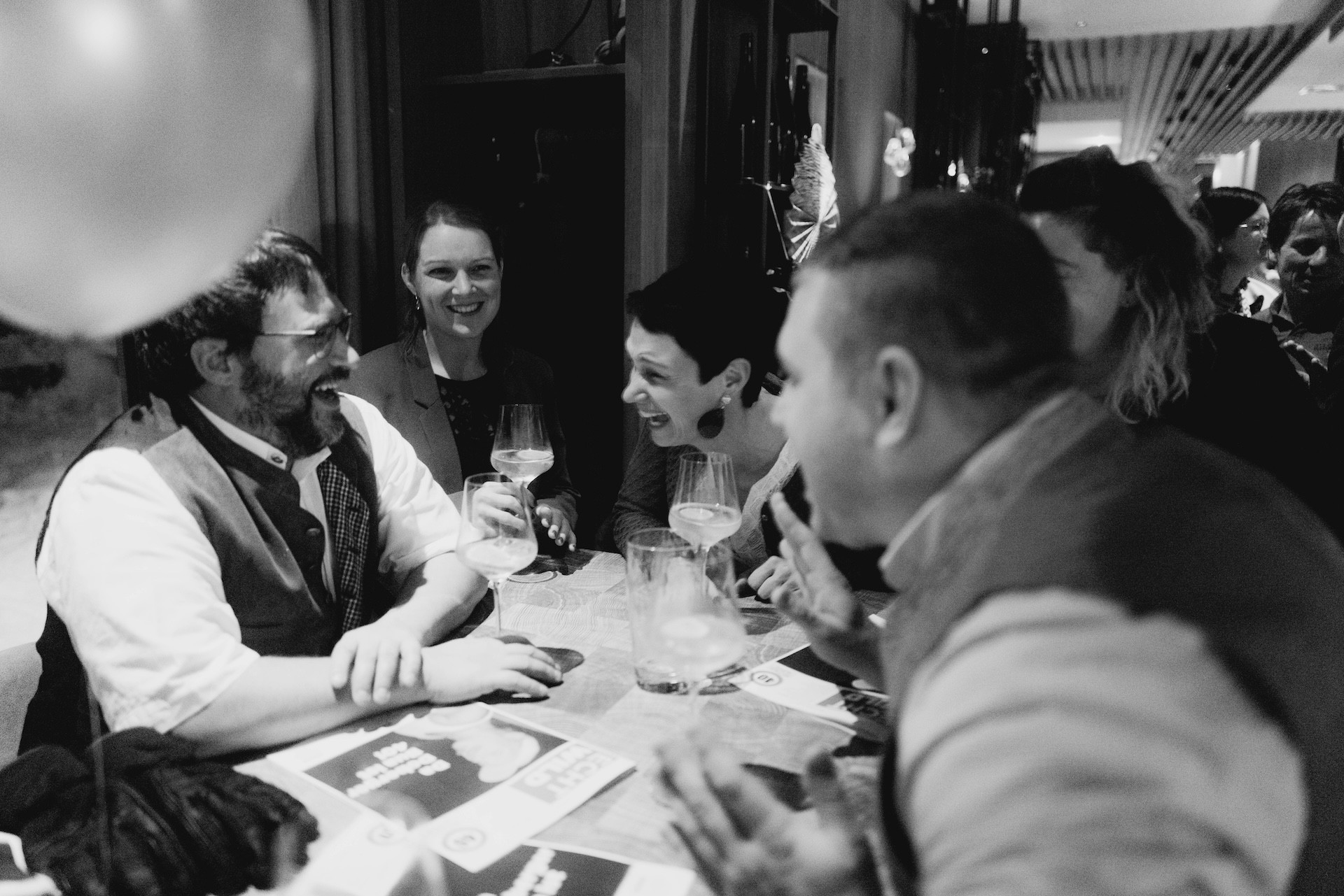 Fröhliche Menschen feiern zusammen bei einer Veranstaltung. Freunde lachen und stoßen an.