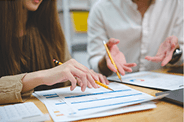 Two professionals discussing a performance consulting plan, reviewing work together in an office setting.