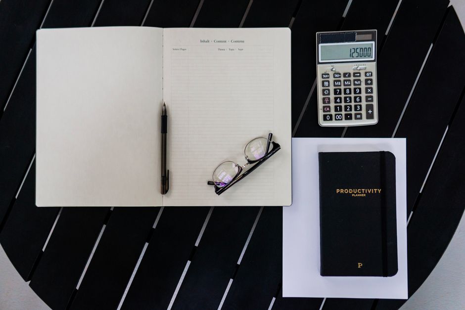 Calculator, agendă și documente pe birou, ilustrând calculul suprataxarii unui contract part-time sub salariul minim în 2026