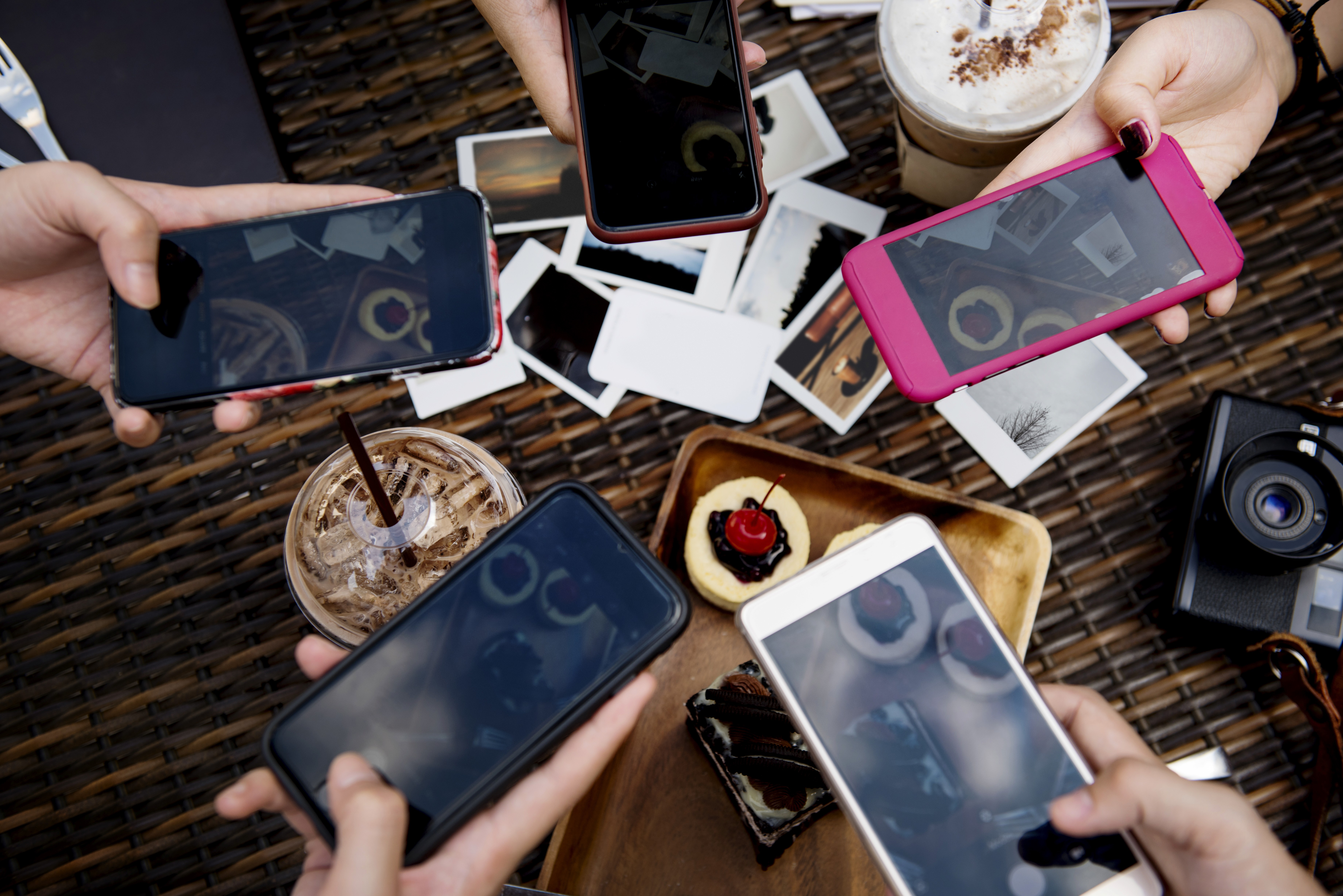 Group of friends taking pictures of desert with their smartphones