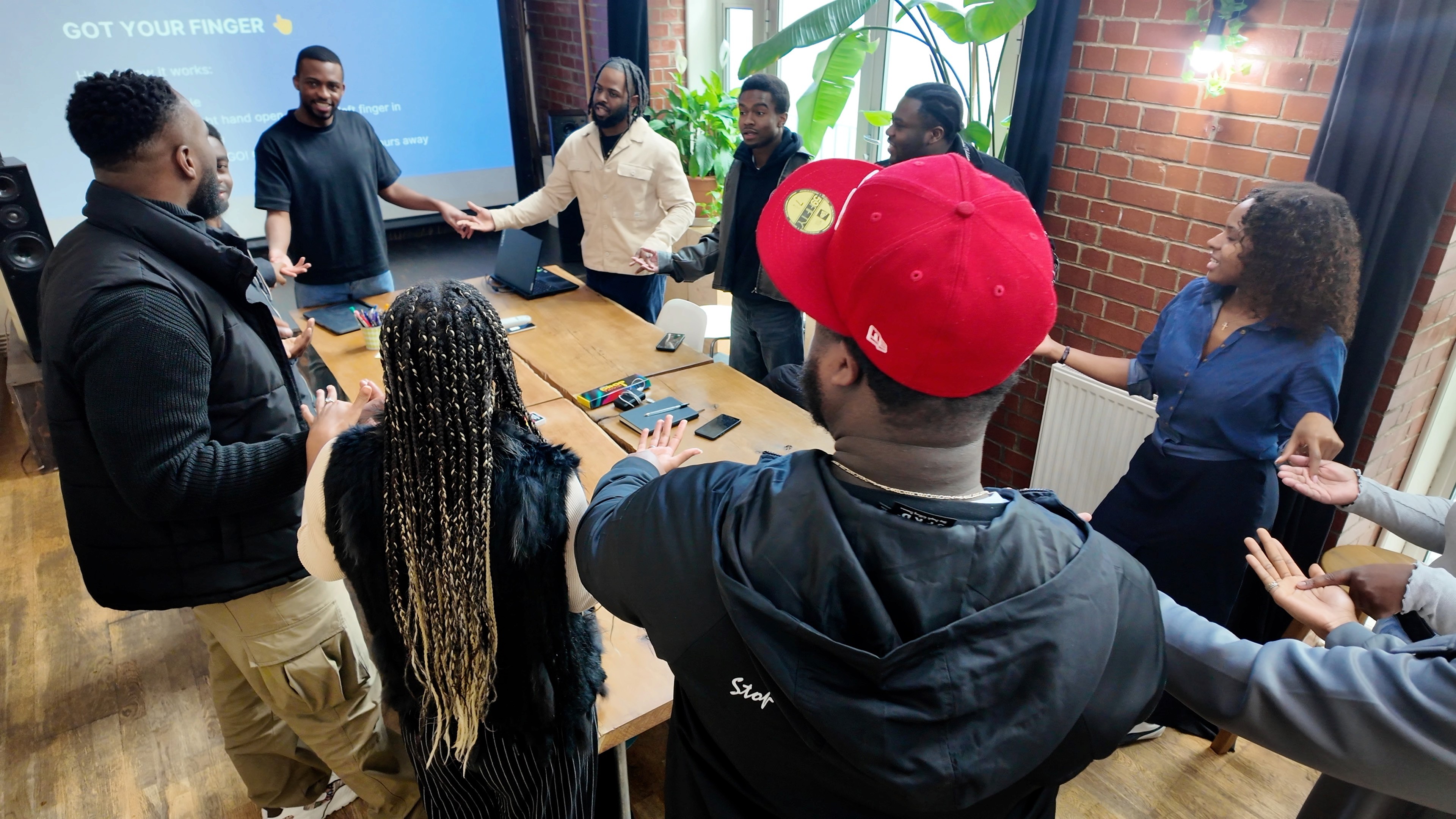 Diverse group in a workshop setting standing and holding hands playing a trust exercise.