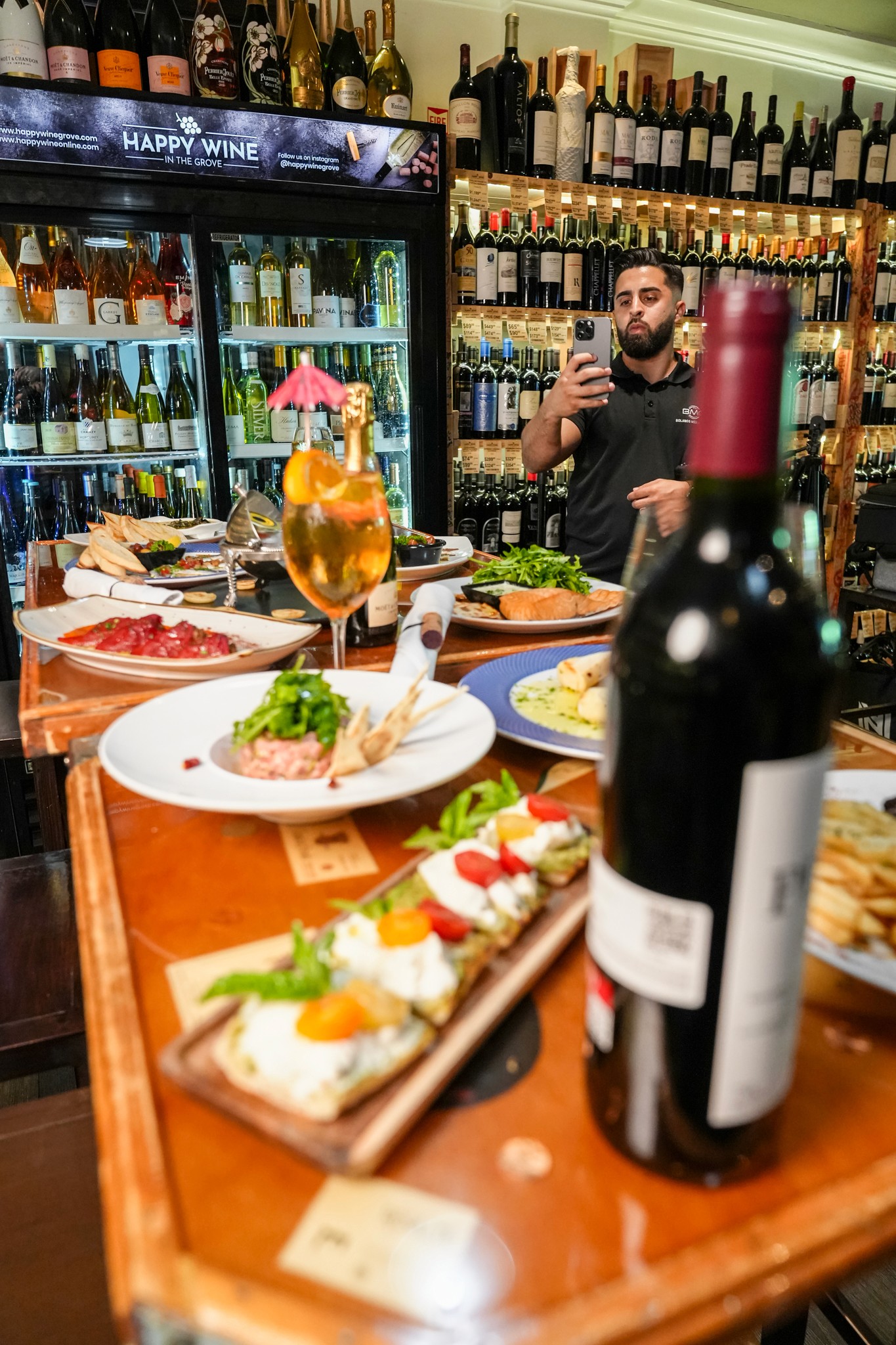 Three individuals gathered around a table, engaged in discussion while examining a laptop.
