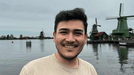 Man smiling with windmills and water in the background.
