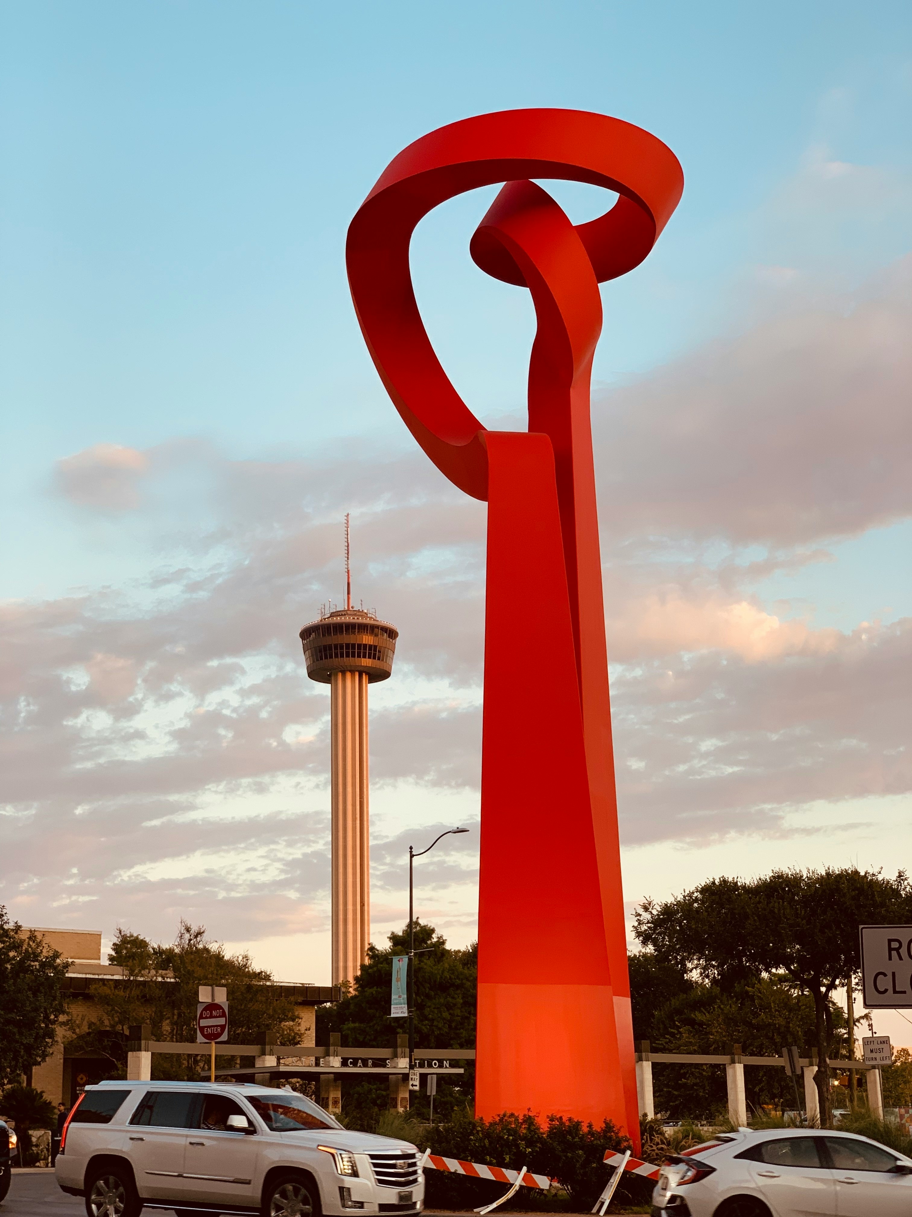 a large red sculpture in the middle of a parking lot