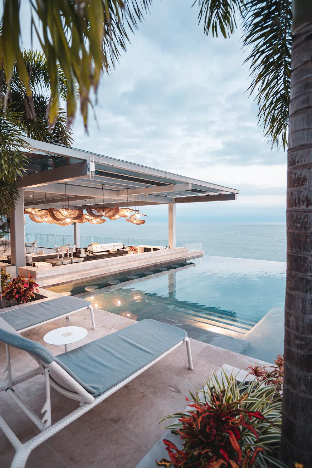 Infinity pool terrace with sun loungers and umbrellas at dusk