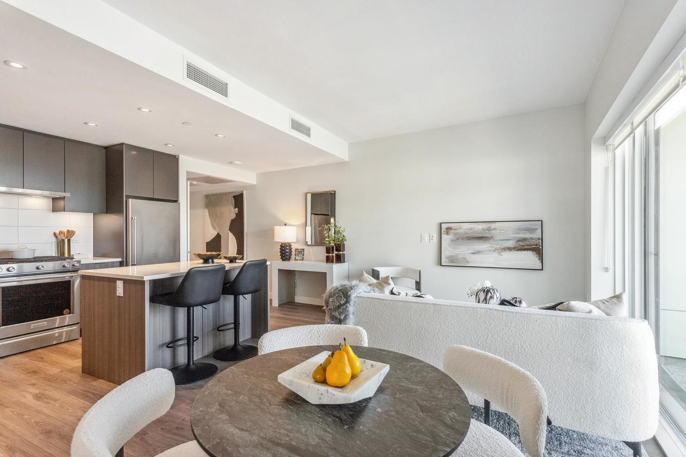 A modern, bright kitchen and dining area with a round table, white decor, and large windows.