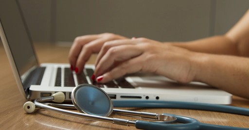 woman typing on keyboard with medical equipment surrounding her