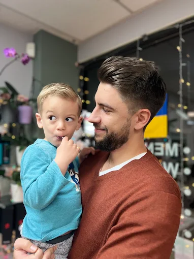 A dad holding his young son at the salon
