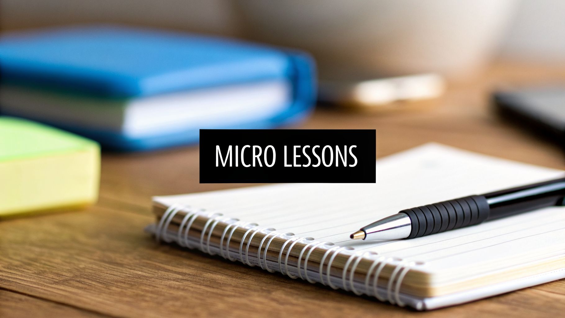 Text 'MICRO LESSONS' over a notebook with a pen and other study supplies on a wooden desk.