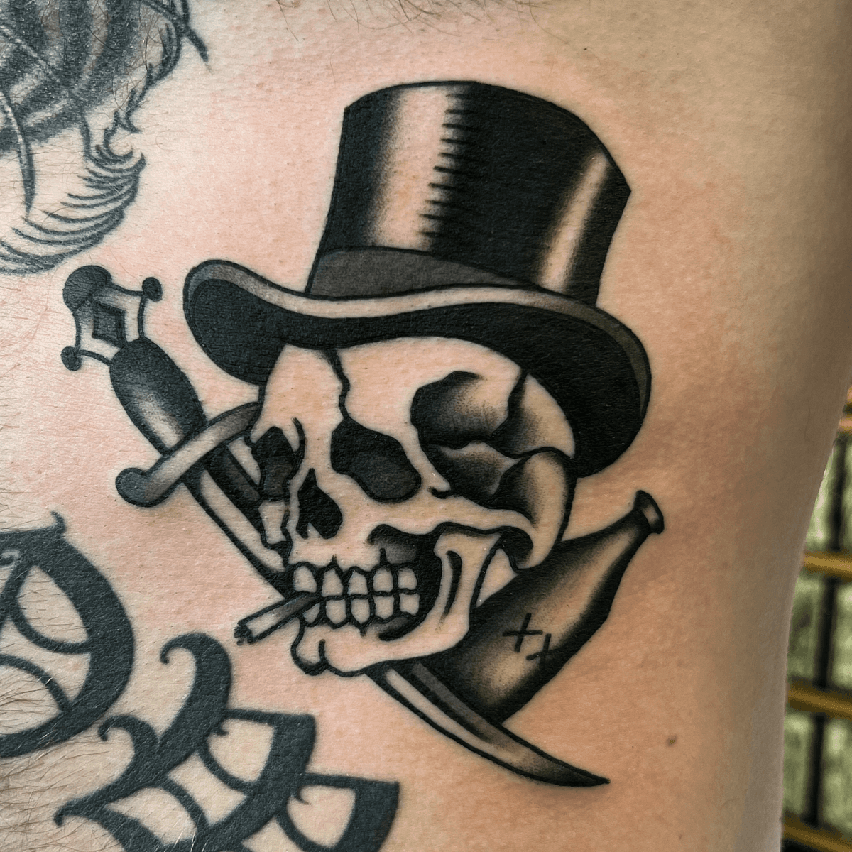 black and gray tattoo of a skull in a top hat with a dagger