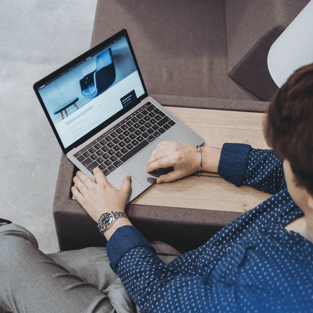 Person nutzt einen Laptop auf einem Holztisch.